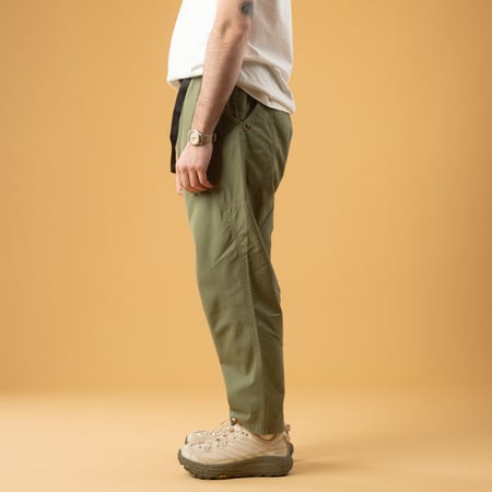 Olive Green GOHEMP High Explorer Pants worn side profile by a person casually walking.