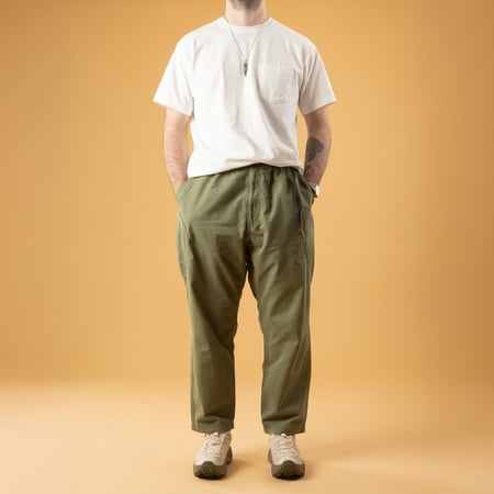 GOHEMP High Explorer Pants Olive Green, front view of the pants worn by a person casually strolling.